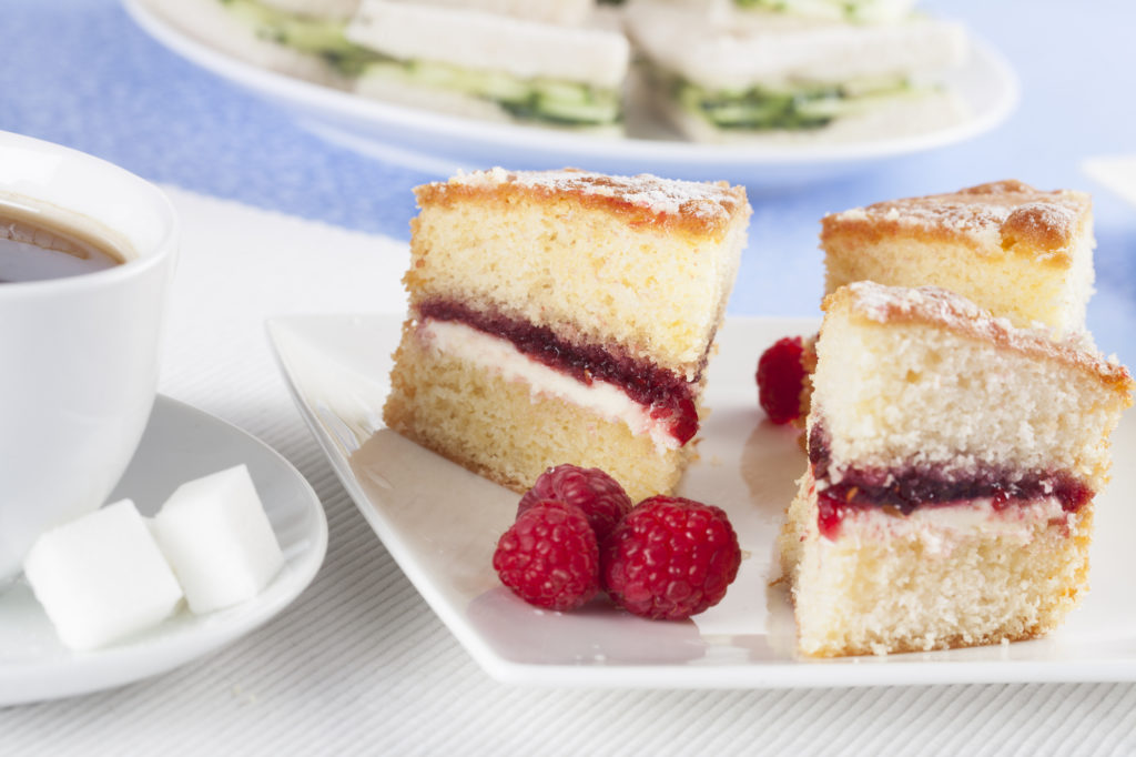 cup of tea with sugar cubes, victoria sponge with raspberries for a perfect afternoon tea